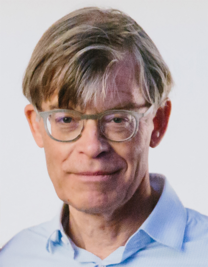 Pasfoto van Jake Wiersma, stedenbouwkundige. Man draagt een bril en een overhemd en heeft kort grijsblond haar.