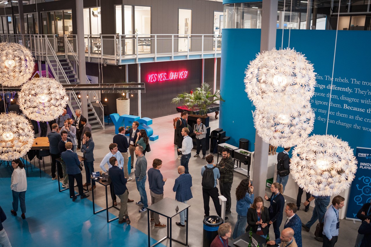 Een groep mensen staat in de aula van Yes!Delft