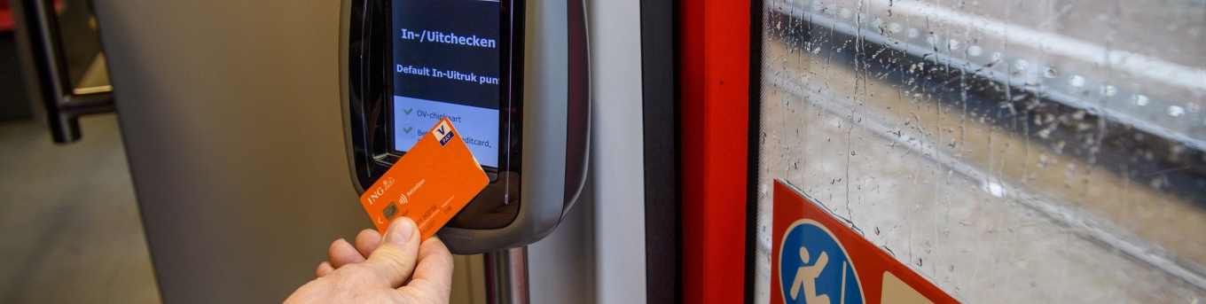 Een reiziger checkt in met een bankpas bij de kaartlezer in een tram.