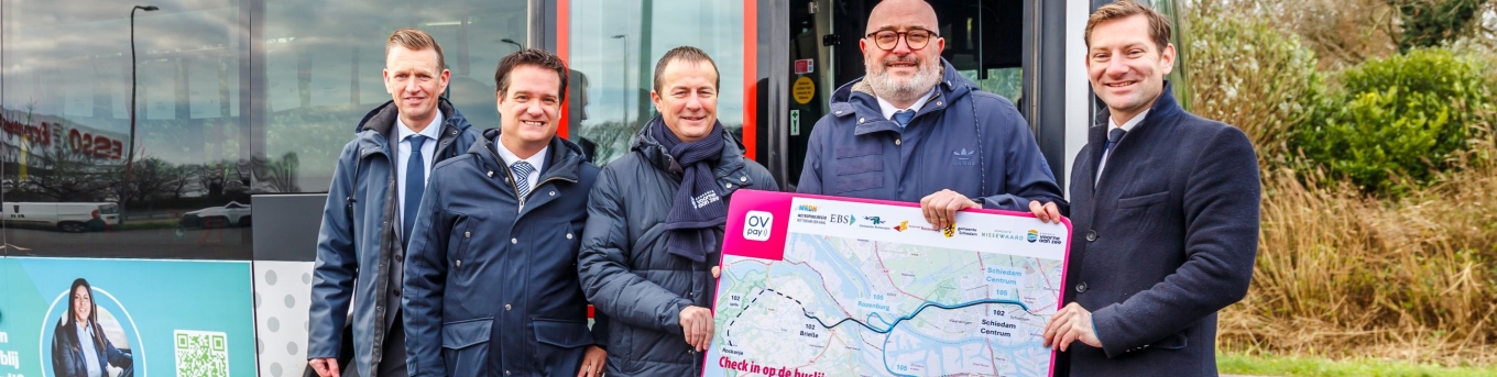 EBS, wethouders Voorne aan Zee en Rotterdam houden een kaart vast met daarop de route van de nieuwe buslijnen. Ze staan voor een bus. V.l.n.r.: Richard Korver EBS, Paul Dullaard Dorpsraad Rozenburg, Peter Schop Voorne Aan Zee, Pascal Lansink-Bastemeijer Rotterdam en Jeffrey Keus MRDH.