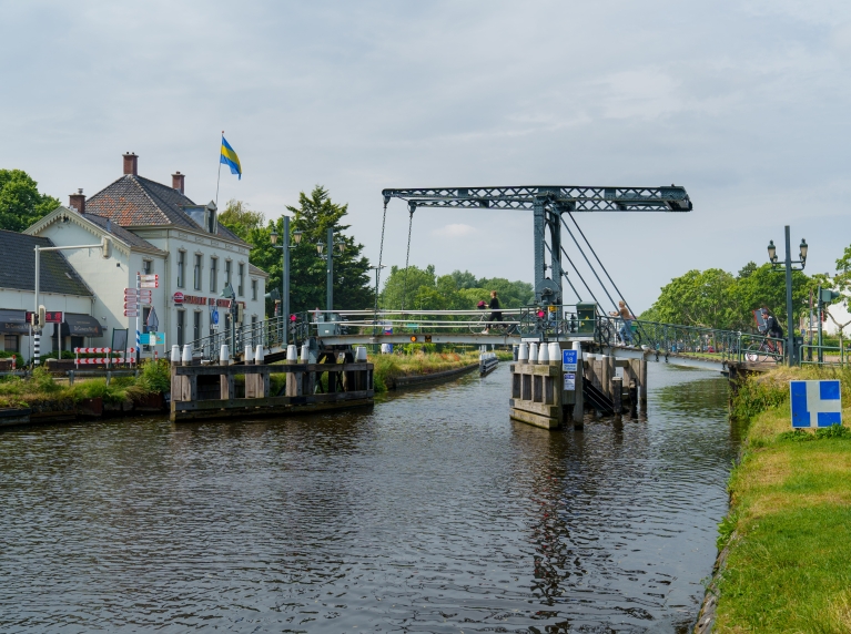 De Nieuwe Tolbrug gezien vanaf het water, fietsers gaan lopend met de fiets aan de hand over de brug.