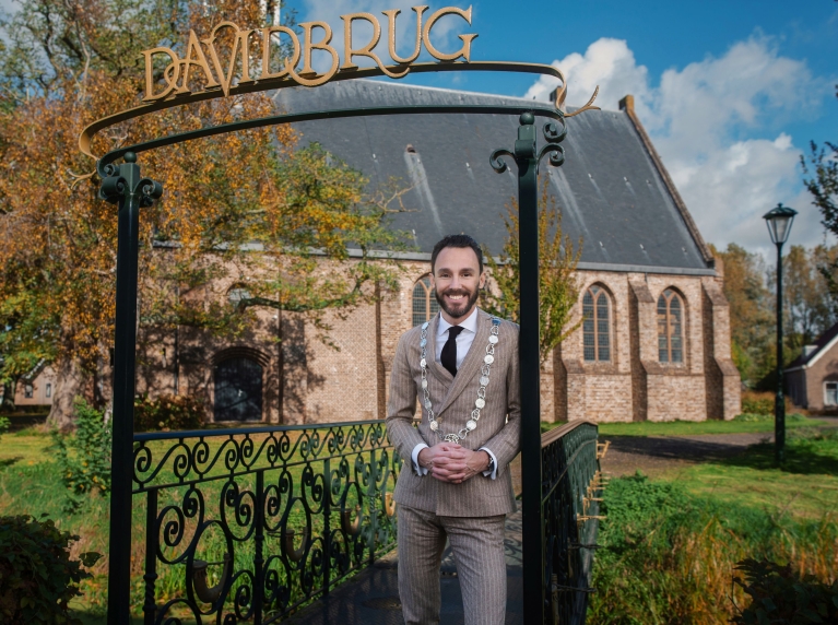 Burgemeester Arno Schepers staat op de Davidsbrug voor een kerk