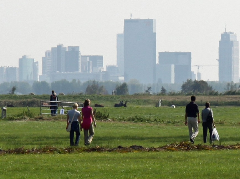 Fotograaf: Henk Groenendaal, Mensen wandelen door de weilanden. Op de achtergrond skyline van Rotterdam.