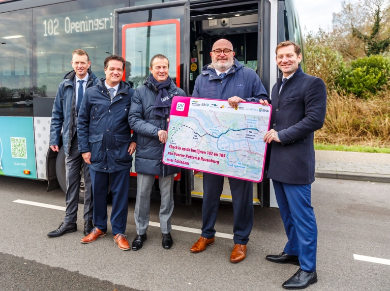 EBS, wethouders Voorne aan Zee en Rotterdam houden een kaart vast met daarop de route van de nieuwe buslijnen. Ze staan voor een bus. V.l.n.r.: Richard Korver EBS, Paul Dullaard Dorpsraad Rozenburg, Peter Schop Voorne Aan Zee, Pascal Lansink-Bastemeijer Rotterdam en Jeffrey Keus MRDH.
