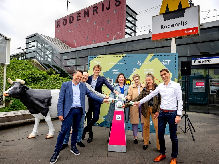 Bestuurders en directeuren openen de Groene Halte Rodenrijs. Ze staan buiten het station en checken in bij een OV-chipkaartlezer.