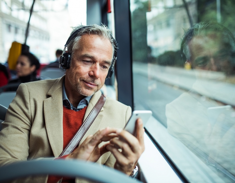Man die met het openbaar vervoer op weg is naar zijn werk en tijdens de reis gebruik maakt van zijn mobiele telefoon.